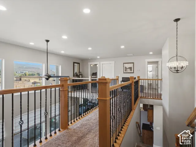 Upper-level landing with wood railings, black iron spindles, recessed lighting, and a ceiling fan