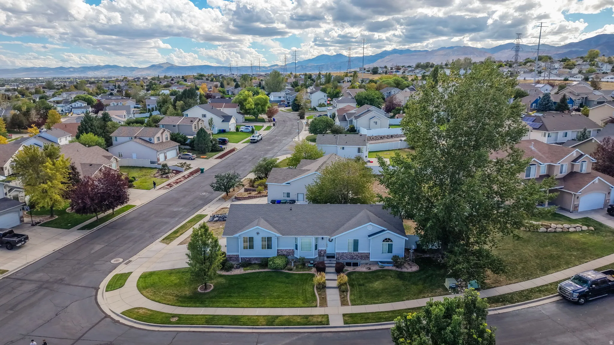 Property with a curved driveway, established landscaping, and a well-maintained lawn, situated on a corner lot