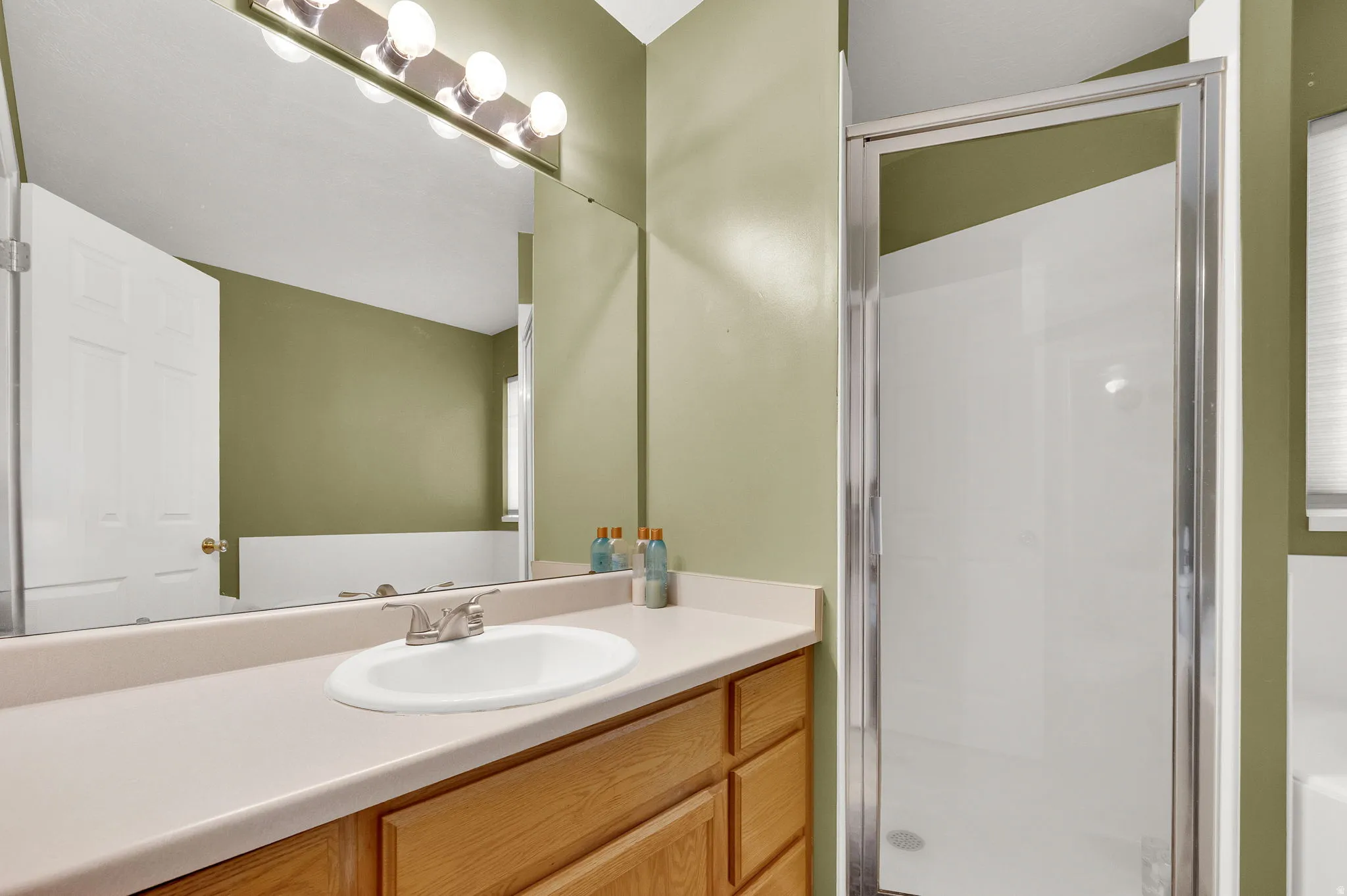 MASTER BATHROOM. Bathroom featuring a single vanity, wood-finish cabinetry, a built-in sink, a wall-mounted mirror, and a standing shower with a glass enclosure