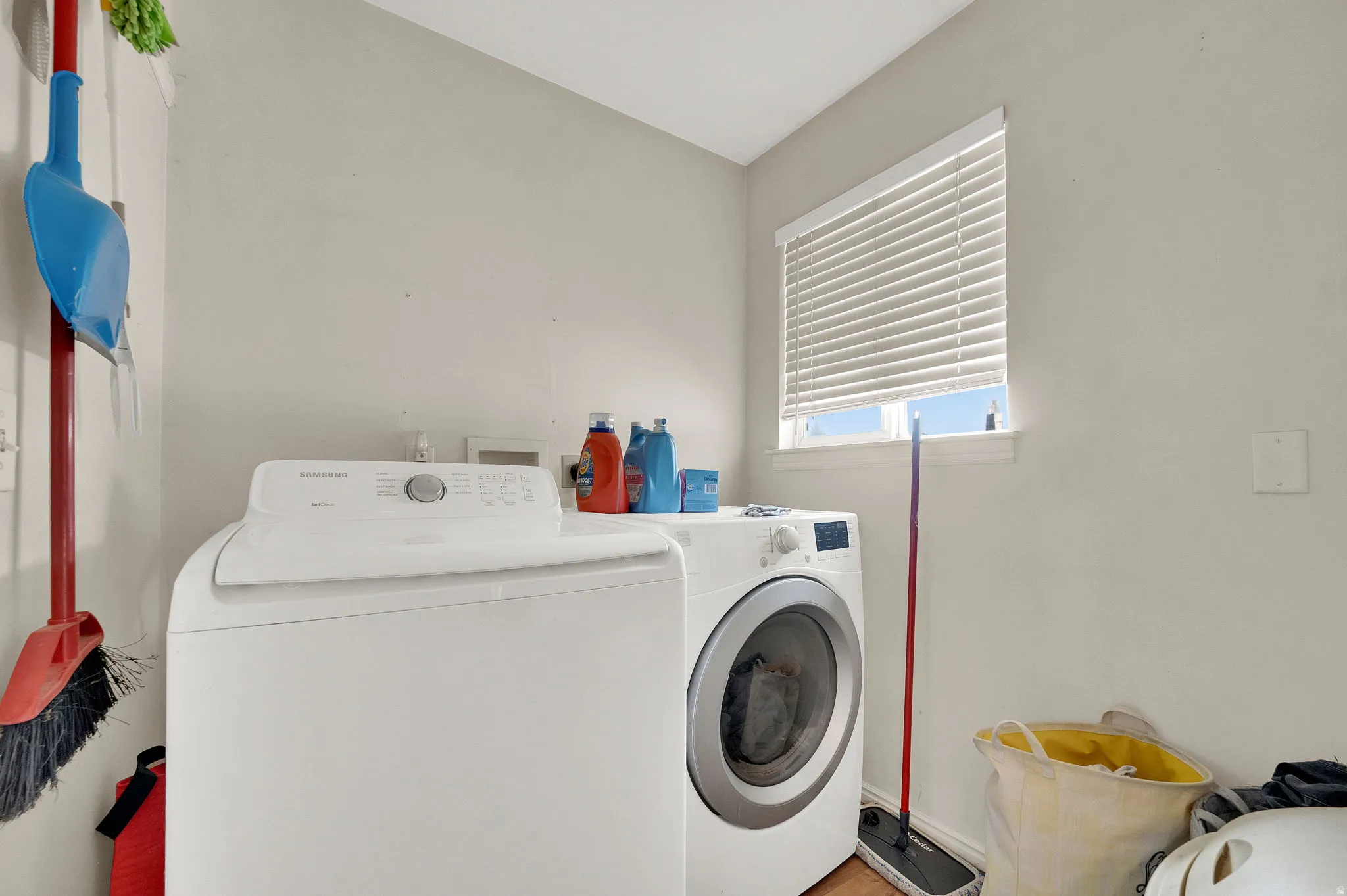Dedicated laundry space with a window and wood-finish flooring