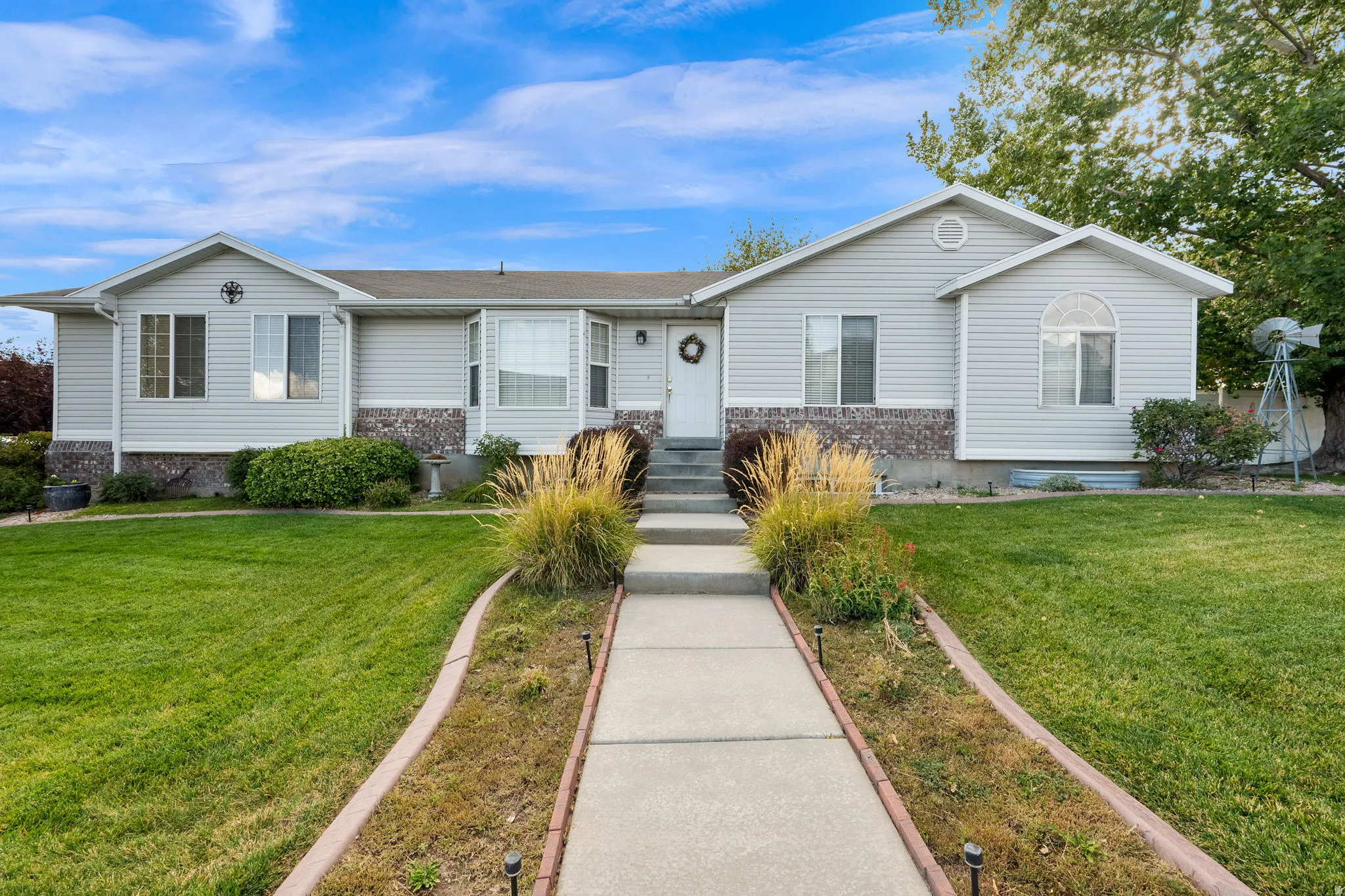 Gray siding exterior with stone veneer accents and a manicured lawn