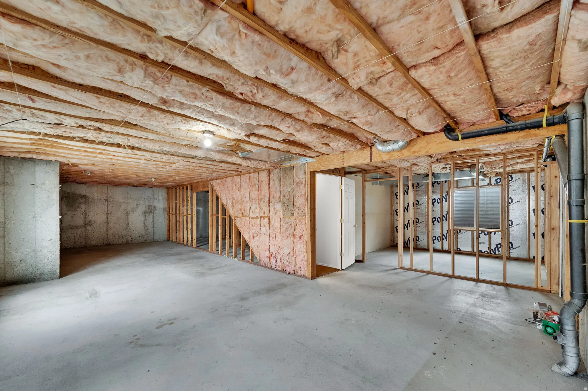 Unfinished basement featuring exposed wood joists, concrete flooring, and framed walls
