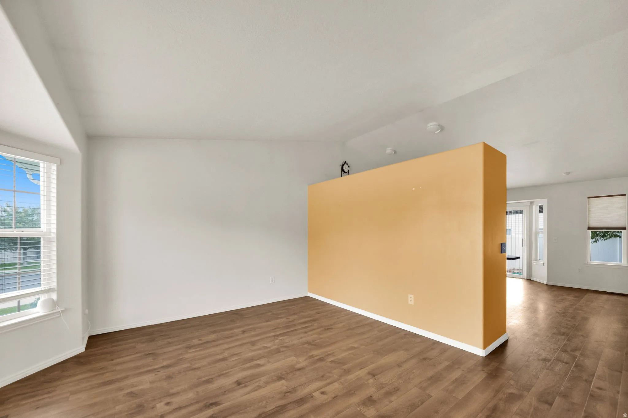 Wood-finish flooring throughout, bright white walls, and a prominent accent wall