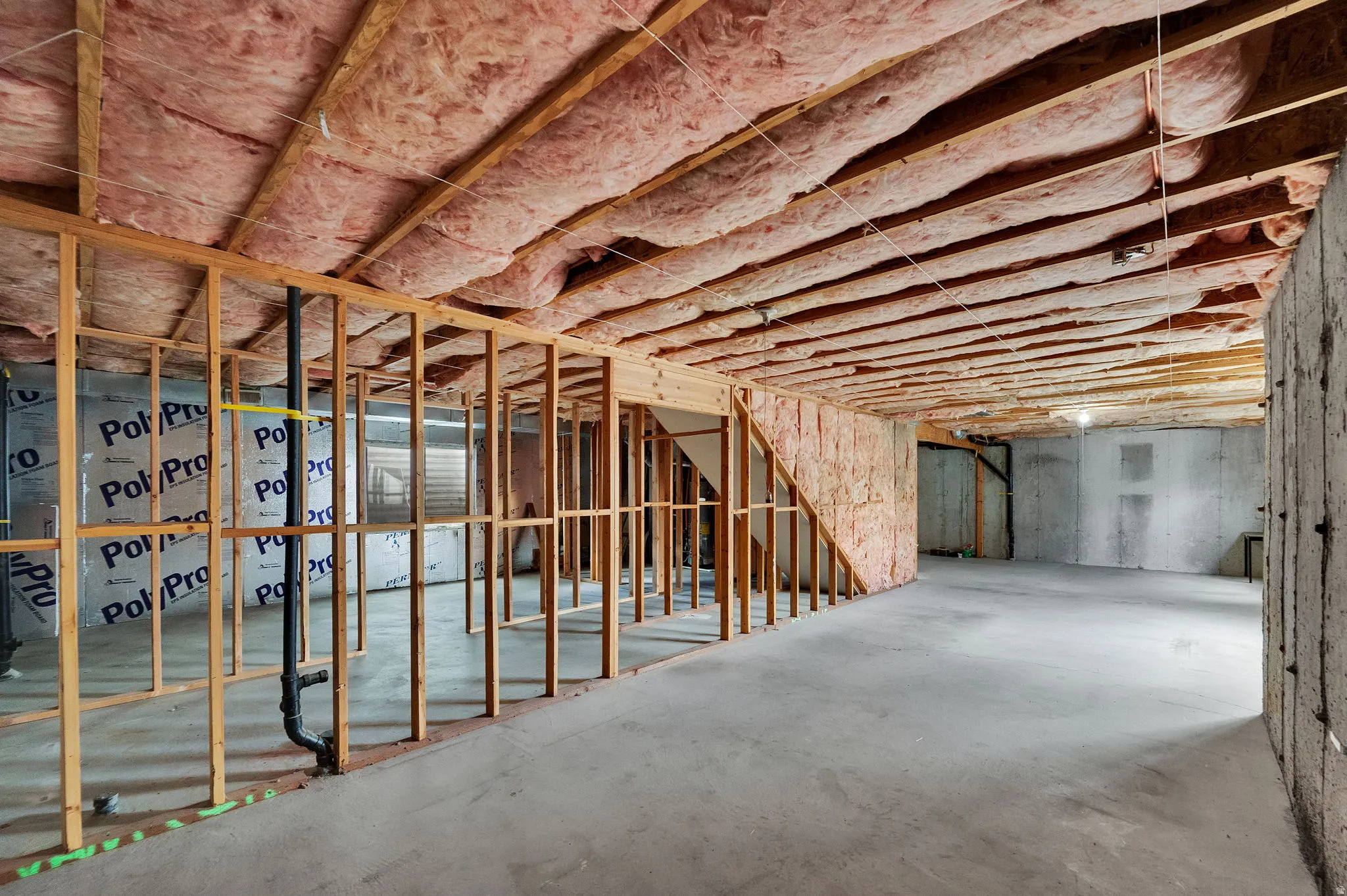 Unfinished lower level featuring concrete flooring, exposed wood framing, and ceiling insulation