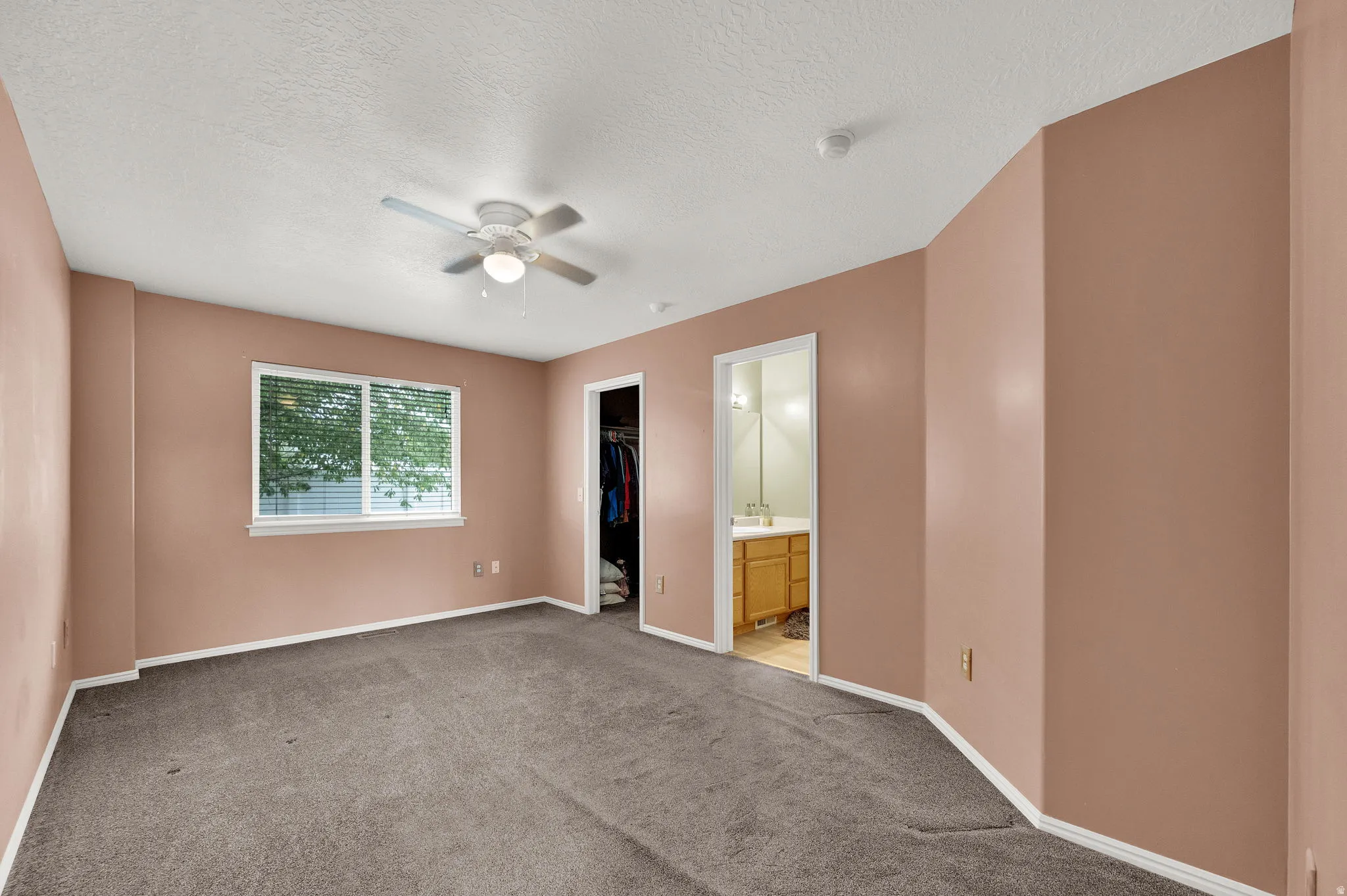 Spacious room with gray carpet flooring and a ceiling fan