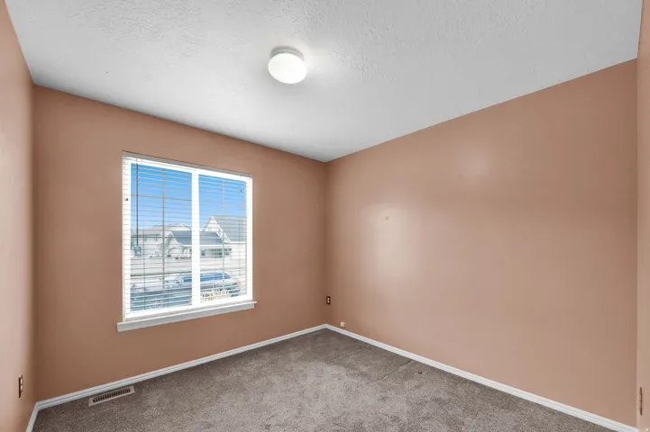 Recessed window with white trim, tan wall paint, textured ceiling, and gray carpet flooring
