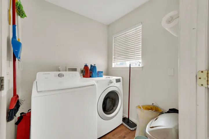 Laundry area featuring wood-finish flooring and a window with blinds