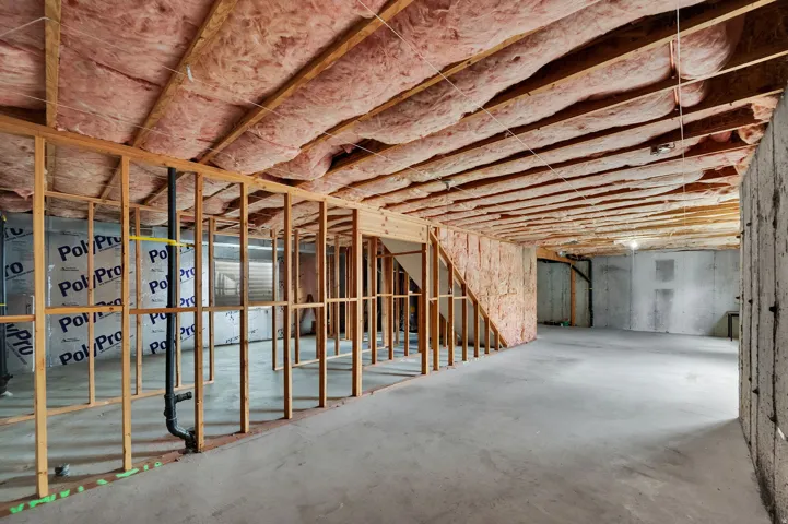 Unfinished lower level featuring concrete flooring, exposed wood framing, and ceiling insulation