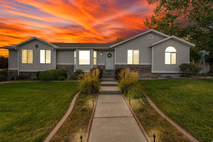 Exterior featuring horizontal siding, stone veneer accents, an arched window, a concrete walkway with landscape lighting, and a manicured lawn