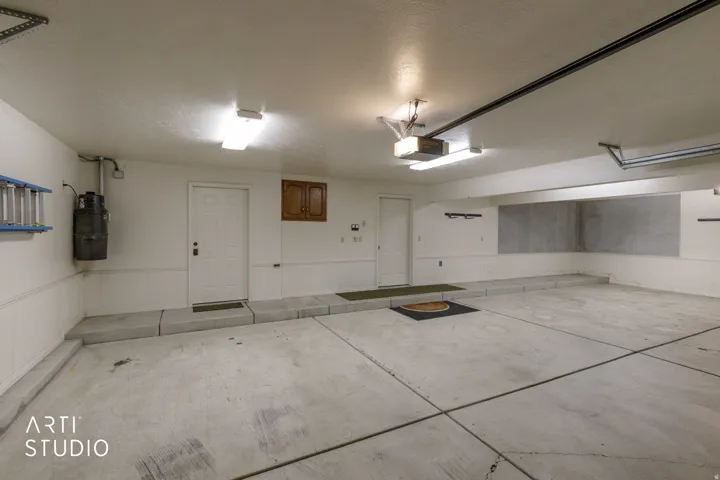 Entry to storage and mud room. Concrete flooring, white paneled wainscoting, two entry doors, wall-mounted cabinetry