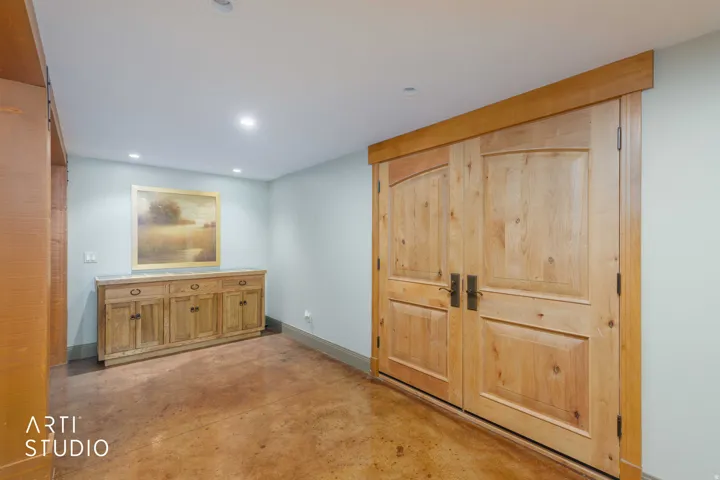 French double entry doors with wood casing, recessed lighting, stained cement finish flooring.