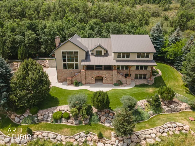Expansive property featuring a multi-story residence with a metal roof, rock and cement siding exterior, and a prominent chimney.