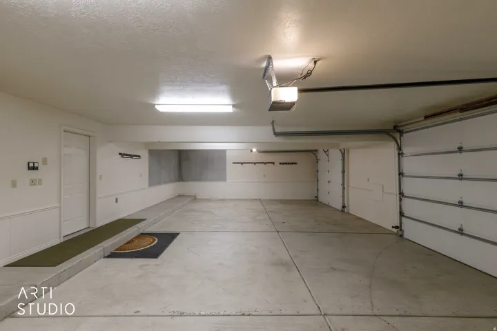 Spacious garage with concrete flooring, multiple garage doors, and overhead lighting