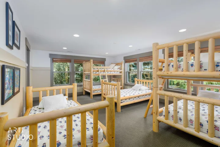 Large girls bunkhouse, lodgepole pine bunk beds, wood-trimmed windows.