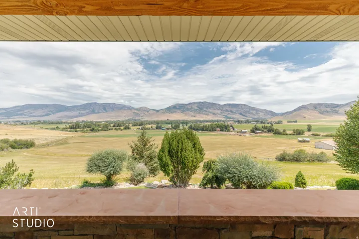 Front porch view to the valley. Expansive landscape featuring distant mountains, open fields, and established trees