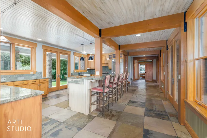 Open-concept kitchen with alder wood cabinetry, neutral-toned granite countertops, and multiple windows