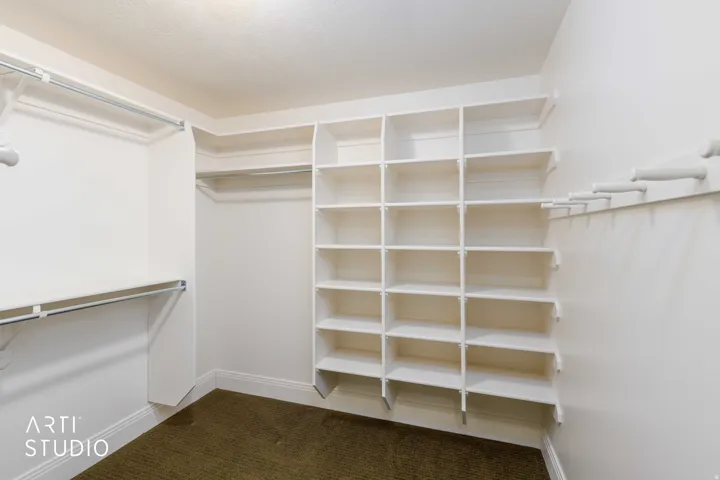 Expansive closet featuring multiple hanging rods, extensive built-in shelving.