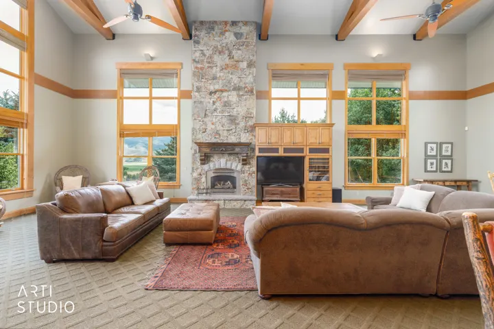 Spacious great room with vaulted ceilings and exposed timber beams, rock gas fireplace, cased wood clad windows with custom moldings.