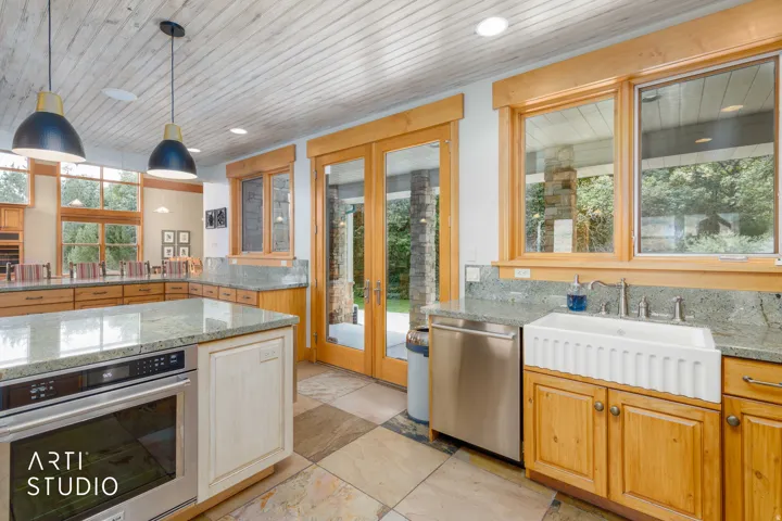 Kitchen featuring wood cabinetry, granite countertops, a farmhouse-style sink, stainless steel appliances, and a wood-paneled ceiling