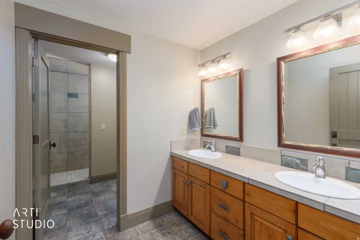 Boys bunk bathroom. Dual vanity with integrated sinks, wood-finish cabinetry, neutral countertop.