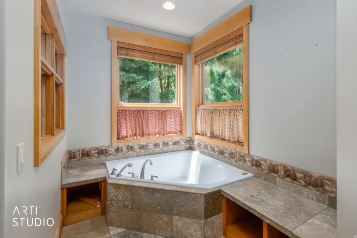 Master bath. Large corner jetted tub with tile surround, custom tile accents.