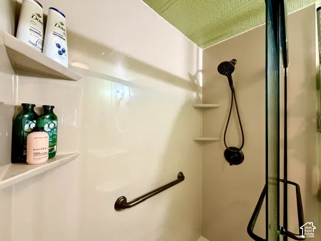 Shower with integrated corner shelving, grab bar, and dark-toned shower fixture