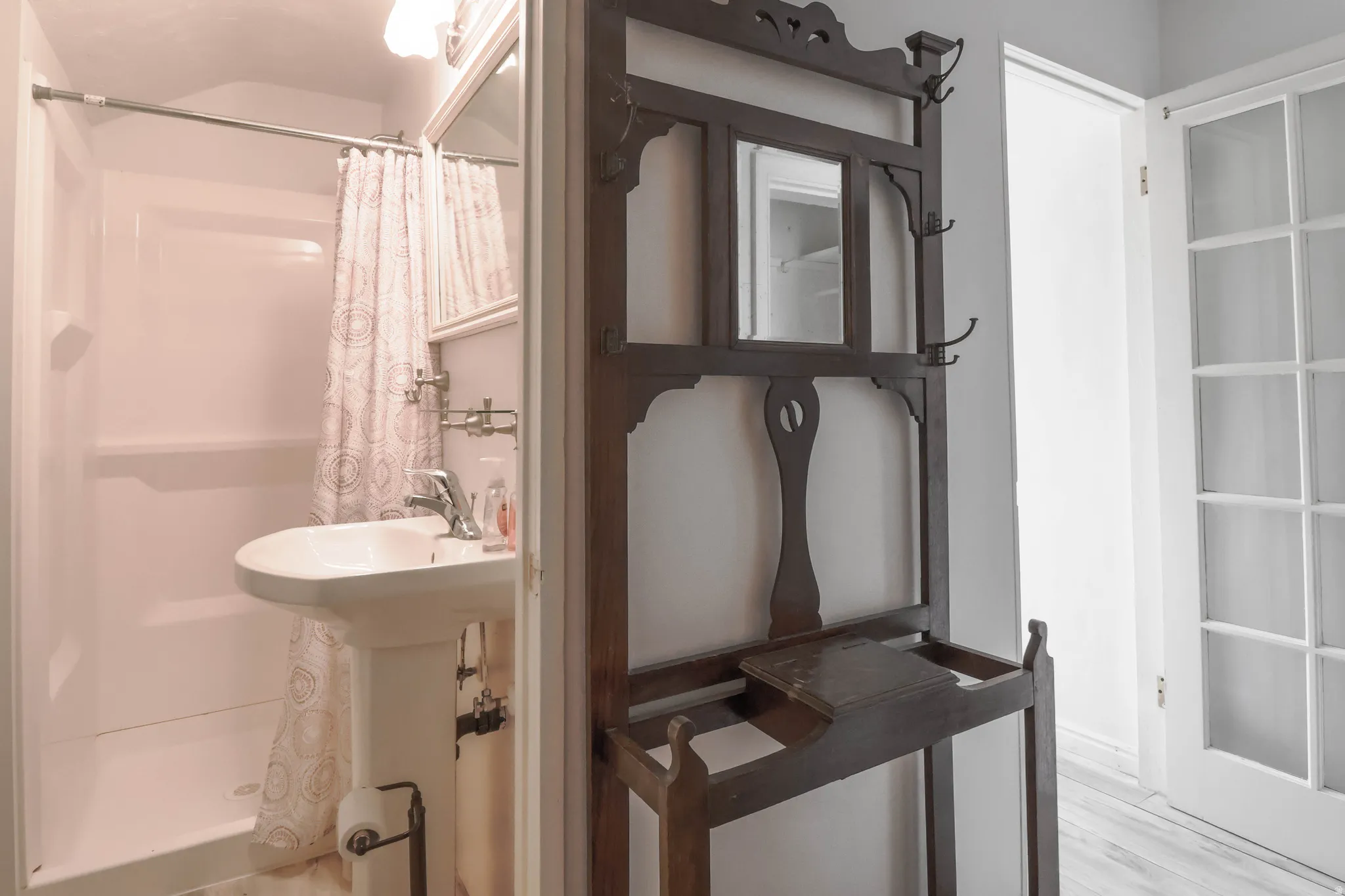 Pedestal sink with chrome-finish faucet and white integrated shower surround