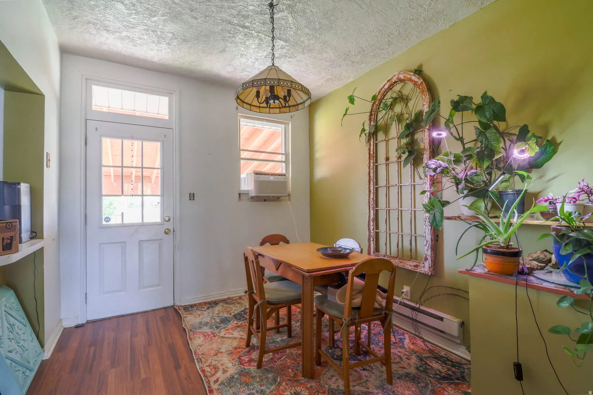 Wood-finish flooring, white paneled door with glass inserts, transom window, and a stained-glass style ceiling light fixture
