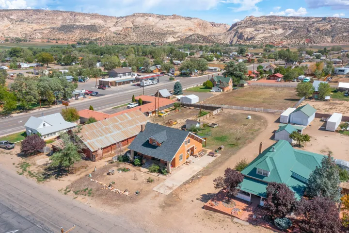 Expansive property featuring a main residence with a green metal roof, multiple outbuildings, and a large open lot