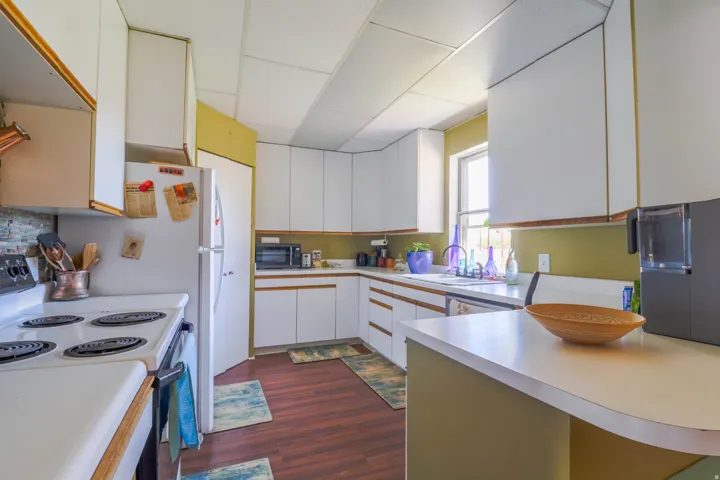 White cabinetry with wood trim, white countertops, built-in sink, and wood-finish flooring