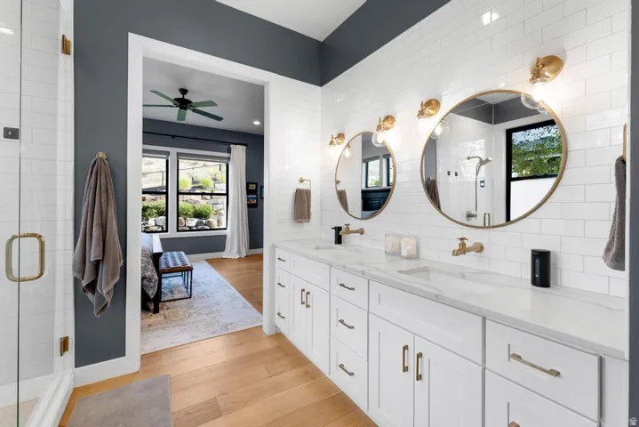 Dual vanity with white cabinetry, wall-mounted brass faucets, and round mirrors