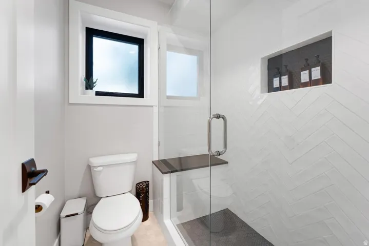 Walk-in shower with clear glass enclosure and built-in shelving