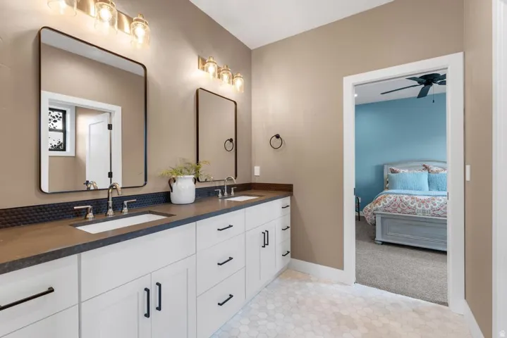Dual vanity with integrated sinks, dark countertop, and decorative tile backsplash