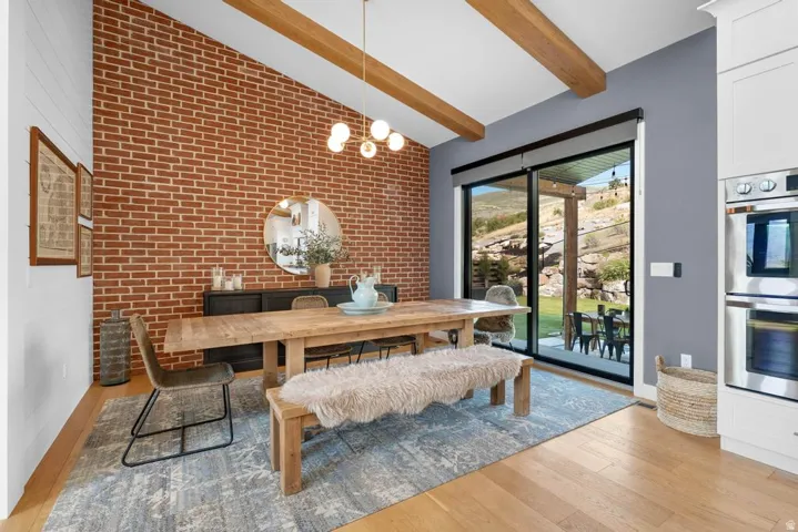 Exposed brick accent wall, vaulted ceilings with wood beams, and a modern globe chandelier