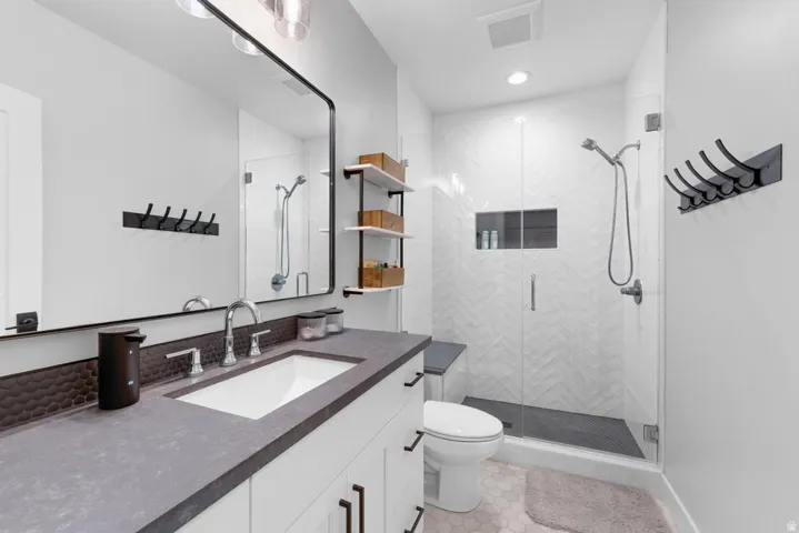 Vanity with a single basin sink, contemporary wall-mounted mirror, and sleek shelving