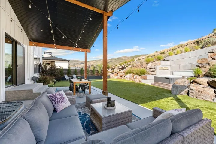 Covered patio with string lighting, paved patio, turf lawn, and a built-in spa