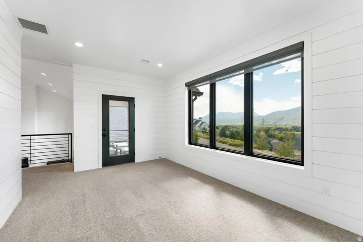 Expansive room featuring shiplap walls, recessed lighting, and a large window with roller shades