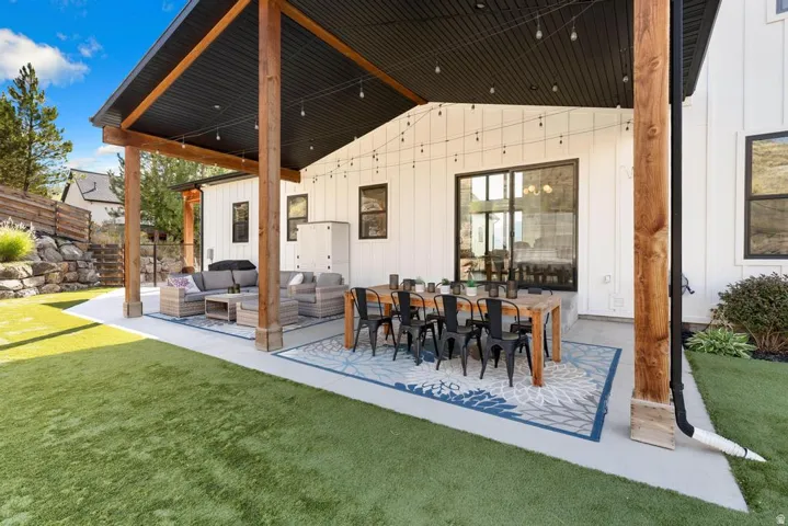 Expansive covered patio with exposed wood beams, concrete flooring, and board and batten siding