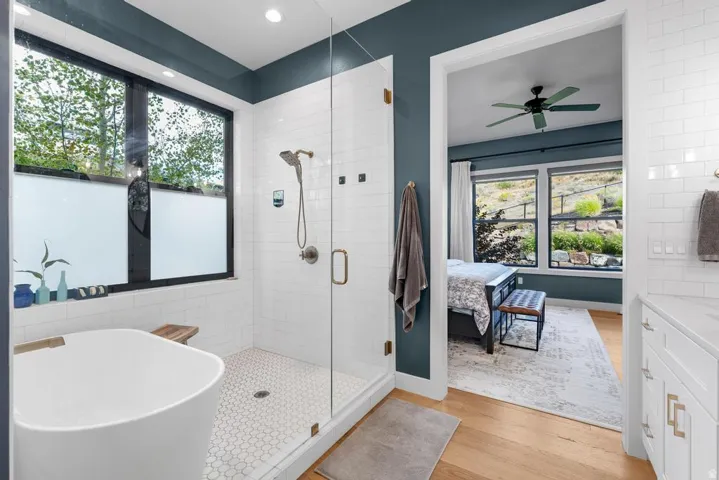 Freestanding soaking tub, glass-enclosed shower with subway tile surround, and hexagonal floor tile
