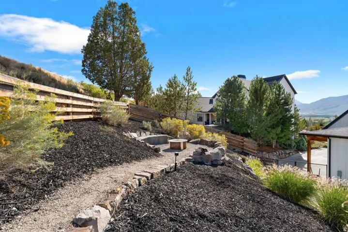 Terraced landscaping featuring a gravel path, rock-lined fire pit area, and a retaining wall