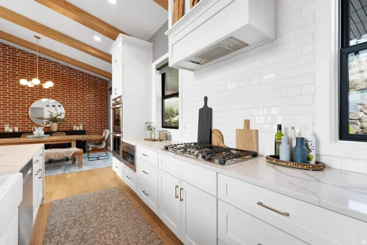 Gourmet kitchen with white cabinetry, built-in appliances, quartz countertops, and a subway tile backsplash