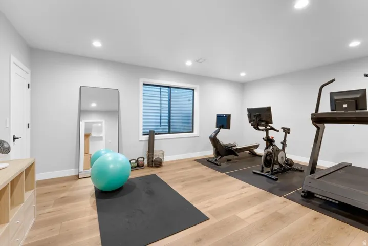 Recessed lighting, wood-finish flooring, and a large window with blinds