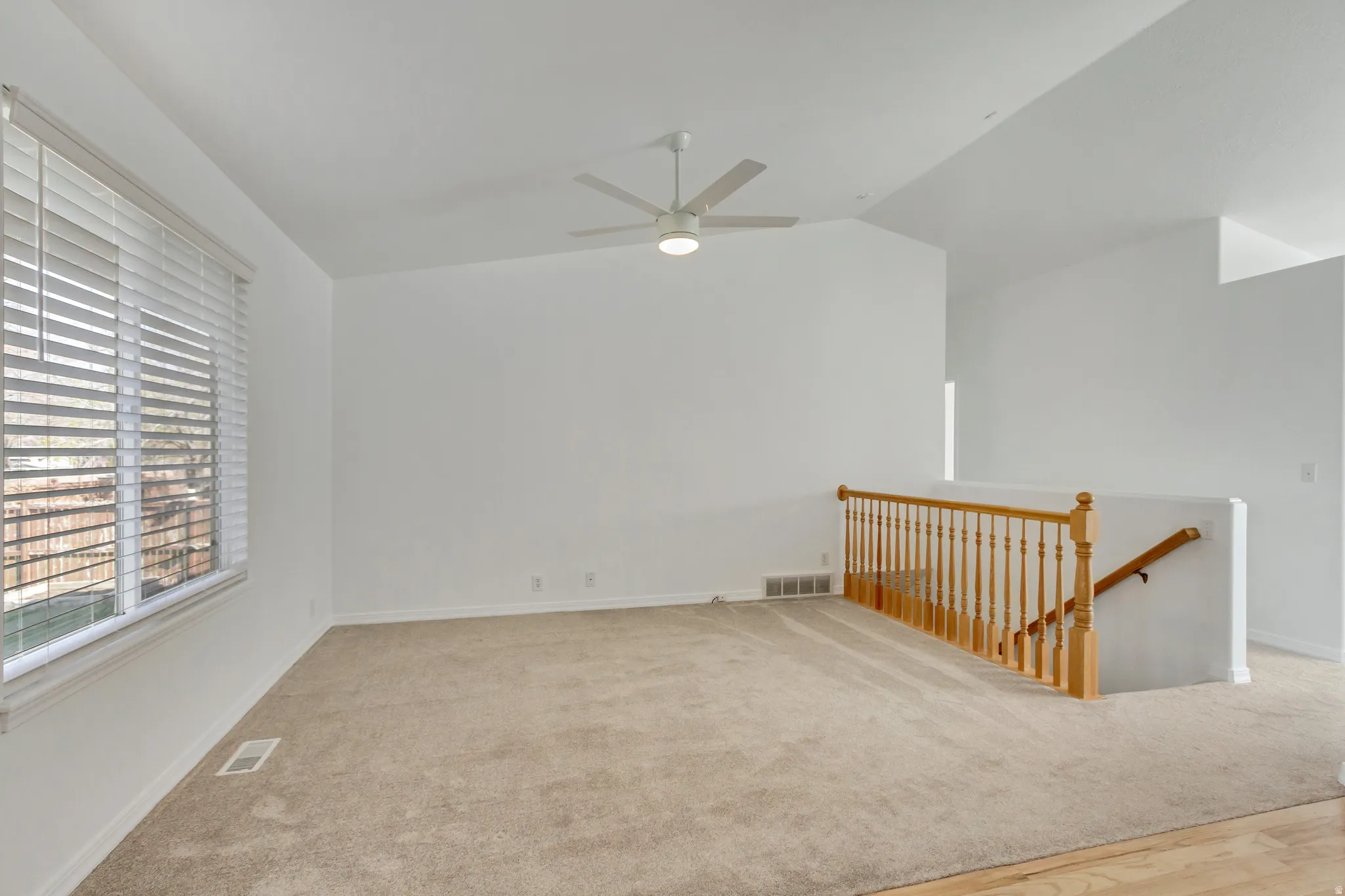 Bright interior with neutral carpeting, white walls, and a ceiling fan
