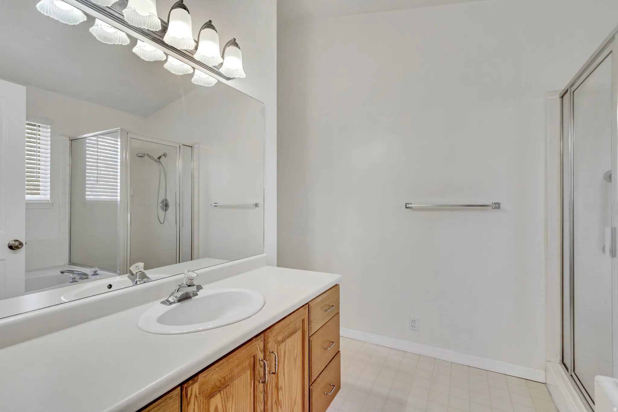 Bathroom with a wood-finish vanity, integrated sink, and an expansive mirror