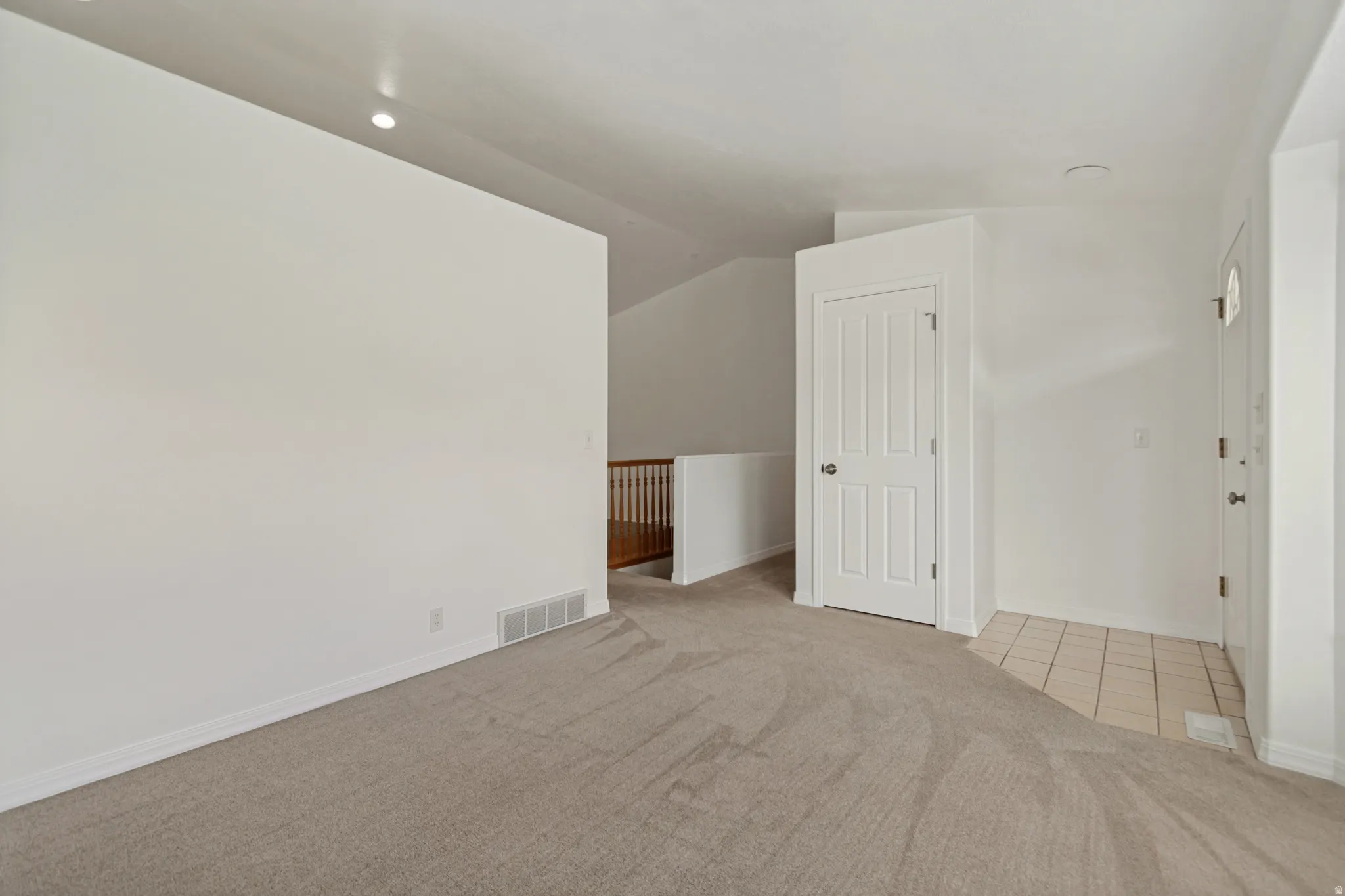 Neutral-toned carpeting extends into the entryway with light-colored tile flooring