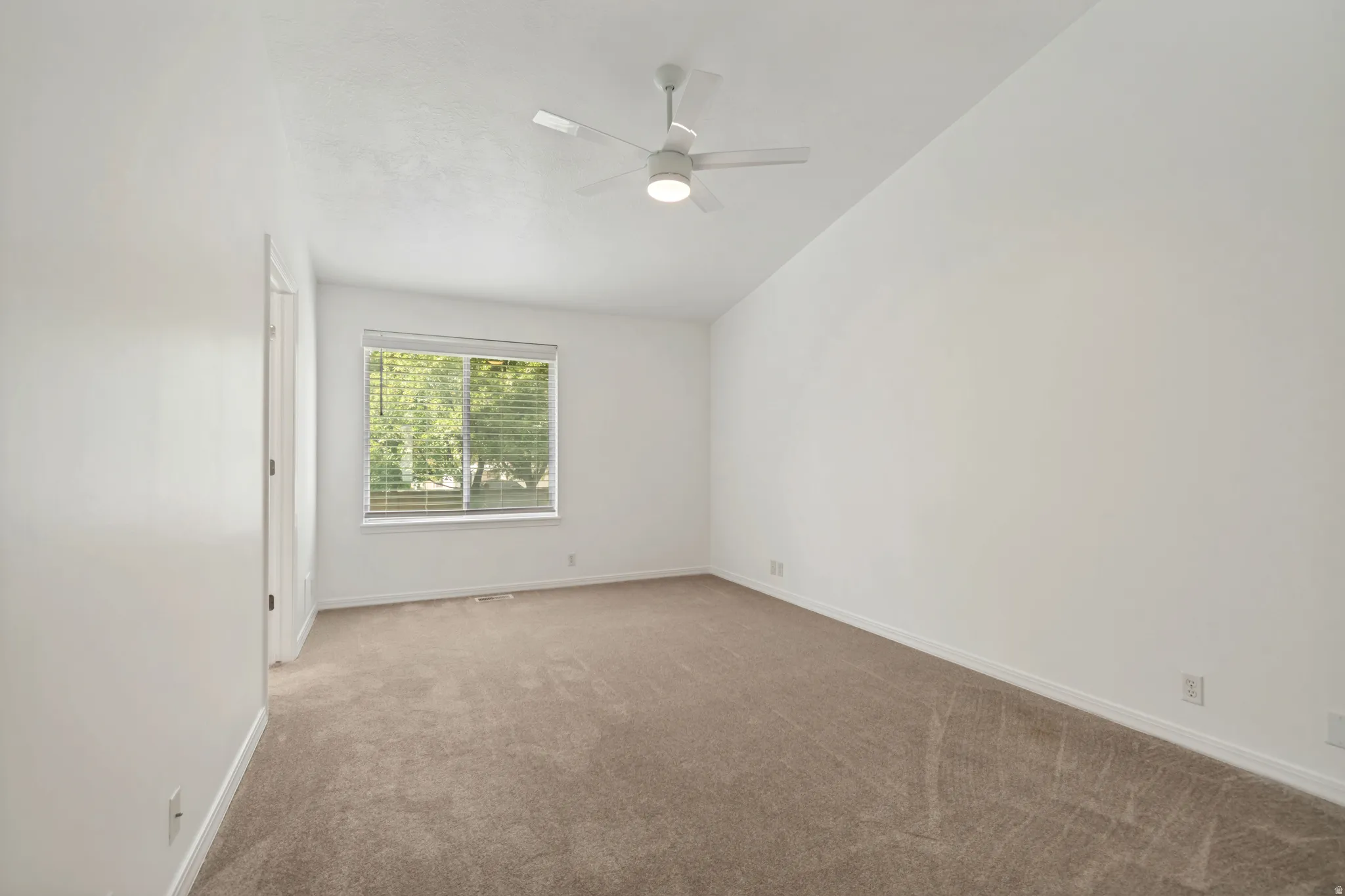 Carpeted room featuring a ceiling fan with integrated lighting, a window with horizontal blinds, and clean white walls