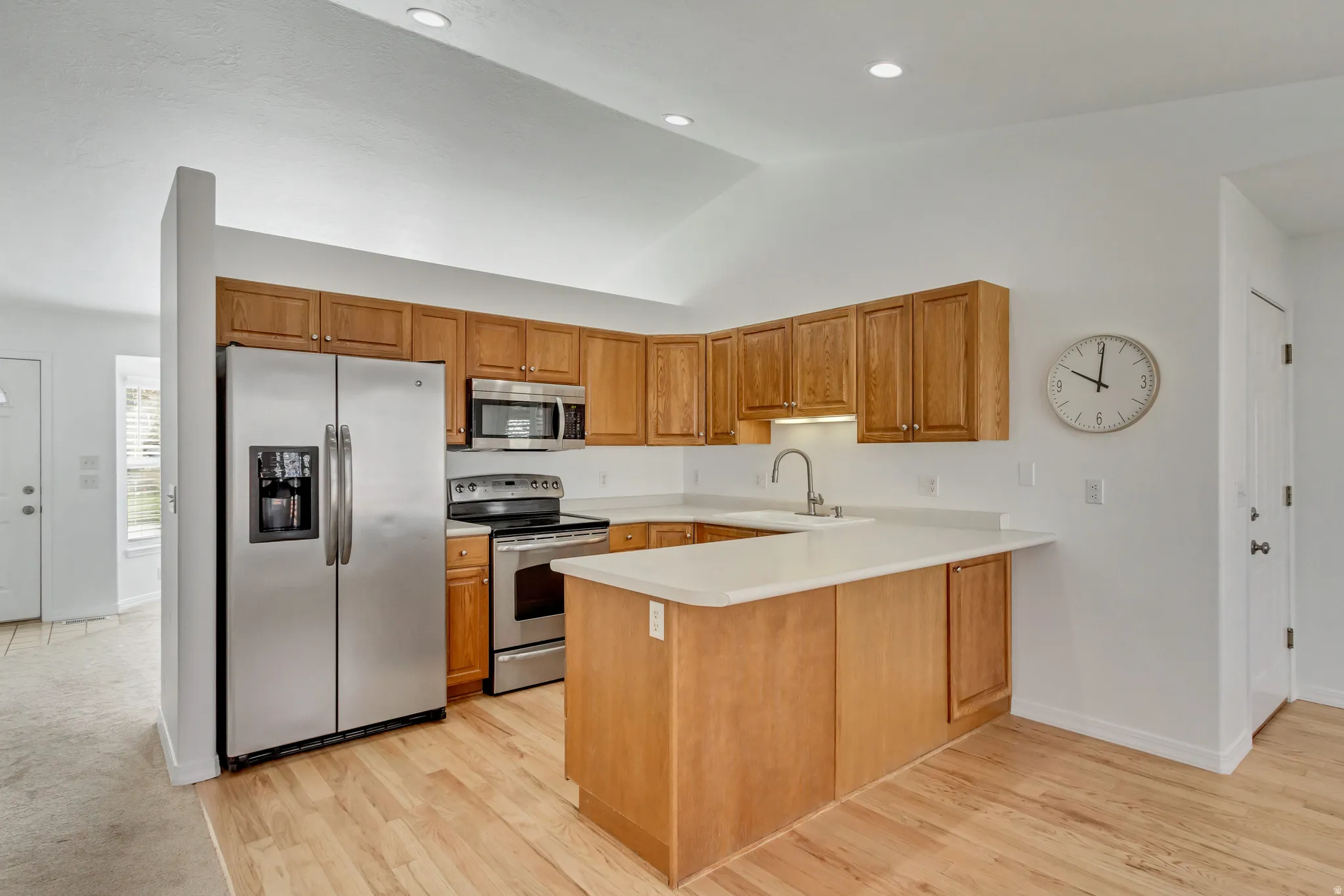 Kitchen featuring wood-finish cabinetry, stainless steel appliances, light countertops, and wood-finish flooring