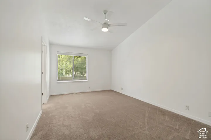 Carpeted room featuring a ceiling fan with integrated lighting, a window with horizontal blinds, and clean white walls