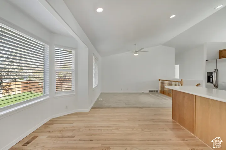 Vaulted ceilings, recessed lighting, light wood-finish flooring, white bay windows, and a ceiling fan