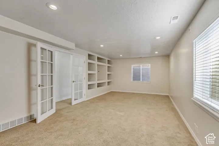 Recessed lighting, built-in shelving, glass-paneled French doors, and two windows with blinds